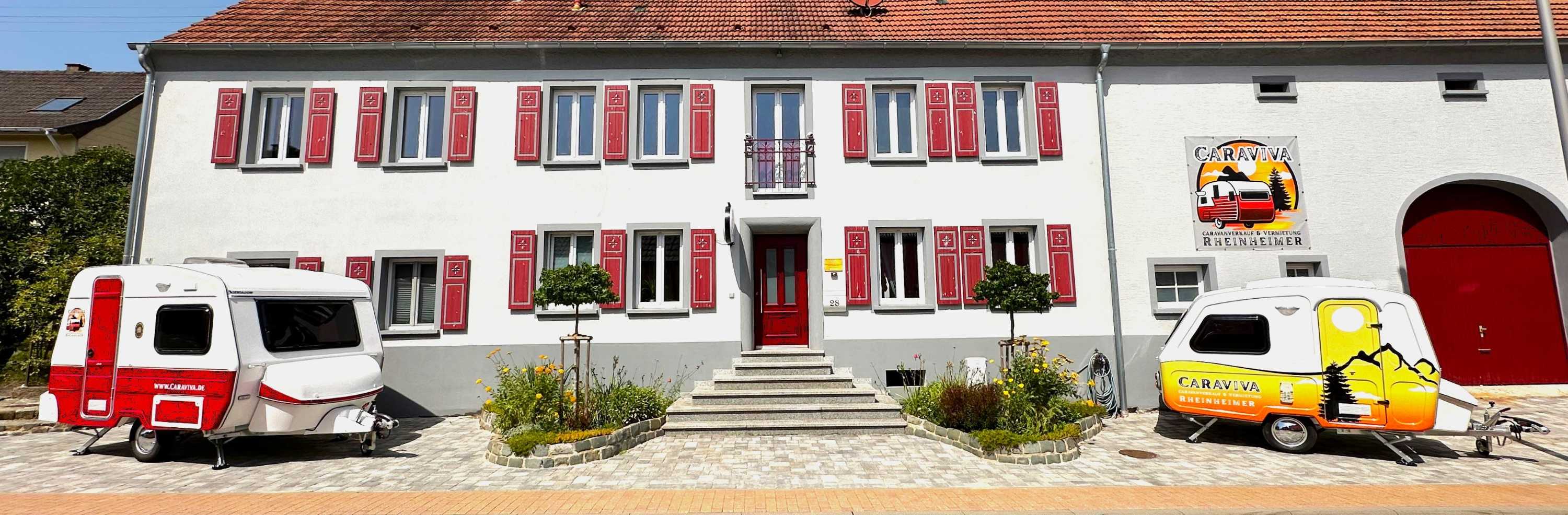 Caraviva Standort in Konken: Gebäude mit roten Fensterläden und zwei Mini-Wohnwagen davor